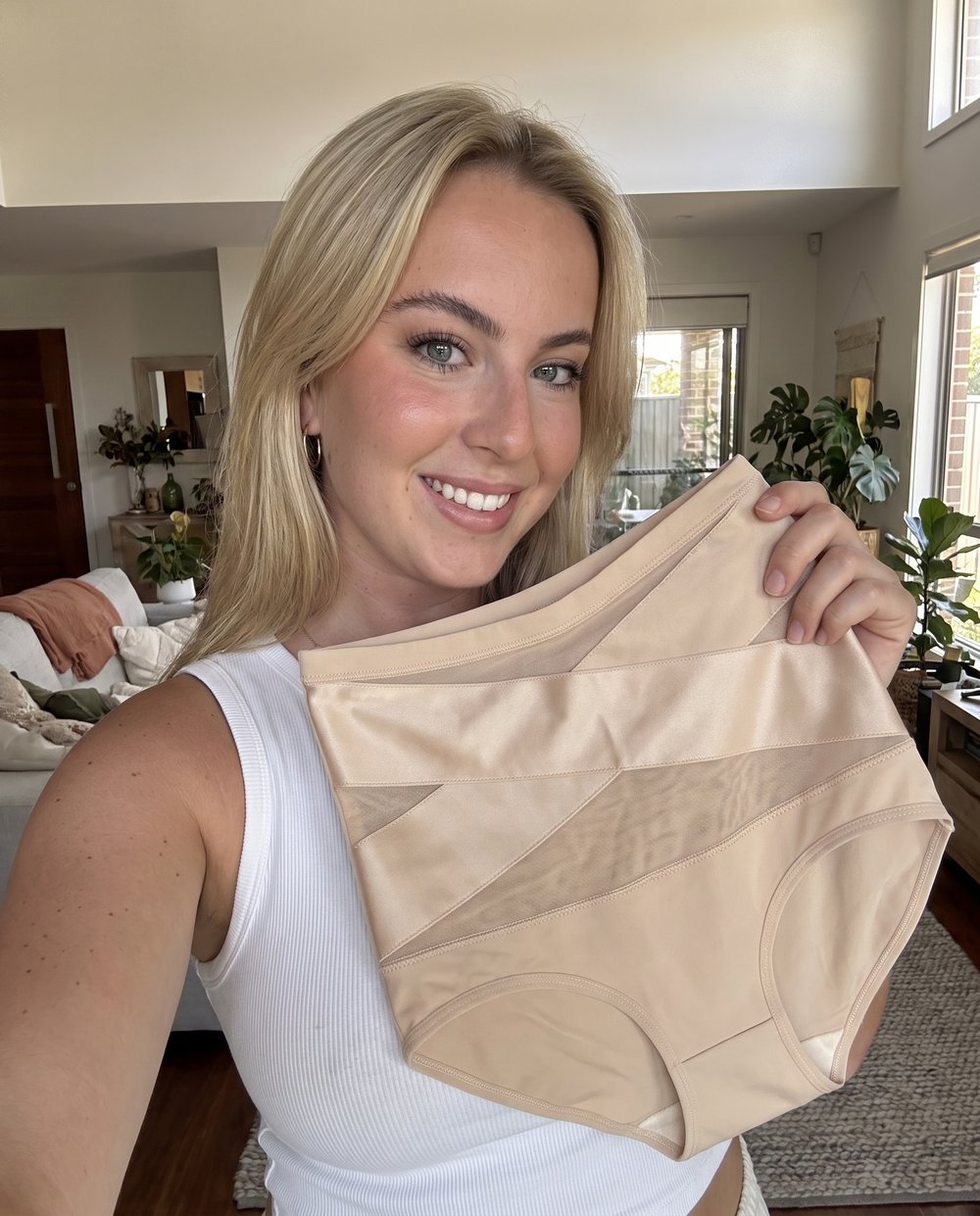 Mujer sonriente mostrando la faja FuerzaMía de talle alto en color beige